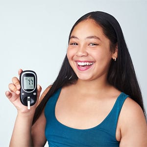 girl smiling holding blood sugar monitor
